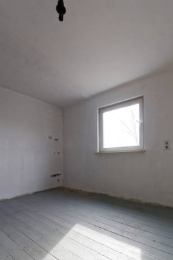 Tamirat sırasında stüdyonun boş beyaz odası. Döşeme tahtaları birinci kat boyalıdır..