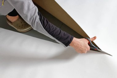 Kendi el yapımı fotoğraf desteğini hazırlamak için stüdyosunun zemininde makas kesen bir kadın sanatçı..