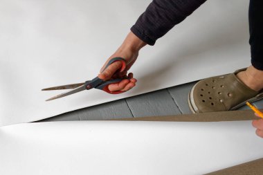 Kendi el yapımı fotoğraf desteğini hazırlamak için stüdyosunun zemininde makas kesen bir kadın sanatçı..