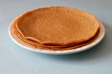 Mavi masanın üstünde büyük bir tabağa istiflenmiş gözlemeler..