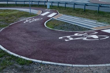 Kırmızı asfalt ve şablonla işaretlenmiş virajlı bisiklet yolu..