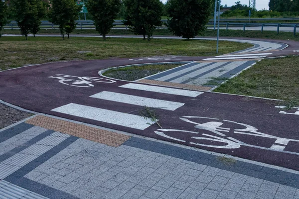 Kırmızı asfalt ve şablonla işaretlenmiş virajlı bisiklet yolu..