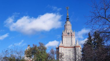 Moskova 'daki eski üniversitenin sonbahar parkı ve güneşli kampüsü mavi gökyüzünün altında