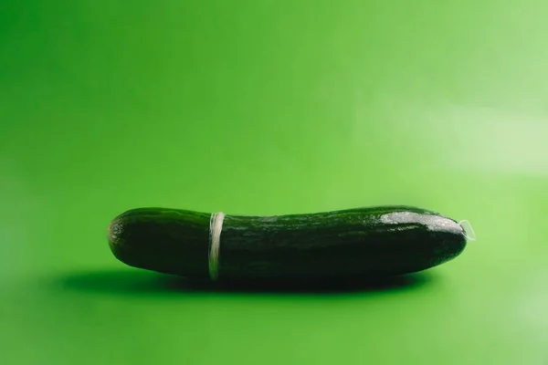 Pepino em um preservativo em um fundo verde brilhante — Fotografia de Stock