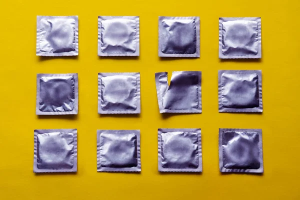 Padrão de muitos preservativos e pacote vazio no fundo amarelo — Fotografia de Stock