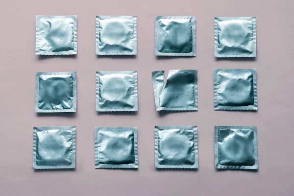 Padrão de muitos preservativos azuis e pacote vazio no fundo rosa — Fotografia de Stock