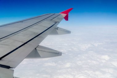 Uçan bir uçağın çatısının altında beyaz kümülüs bulutları.