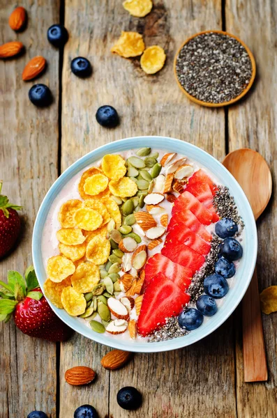 healthy strawberry smoothie bowl with fruits, cereals, seeds and