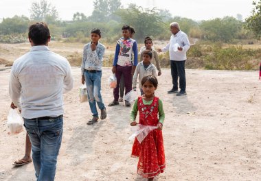 NOIDA, UTTAR PRADESH, INDIA - NOVEMBER 2020: Hindistan 'da Corona salgını sırasında gönüllülerin dağıttığı yiyecekleri toplamak için kenar mahalle veya köy bölgesinden gelen genç çocuklar veya öğrenciler. Topluma geri vermek..
