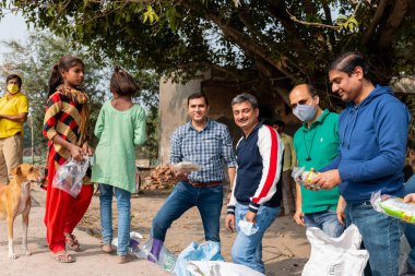 NOIDA, UTTAR PRADESH, INDIA - Kasım 2020: Hindistan 'daki sivil toplum örgütü gençlerinden oluşan bir grup, salgın sırasında yoksul çocuklara ve gecekondu halkına yiyecek dağıtıyor. Zor zamanlarda topluma geri vermek.