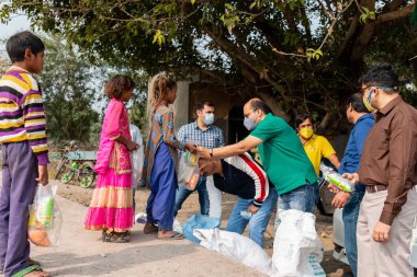 NOIDA, UTTAR PRADESH, INDIA - Kasım 2020: Hindistan 'daki sivil toplum örgütü gençlerinden oluşan bir grup, salgın sırasında yoksul çocuklara ve gecekondu halkına yiyecek dağıtıyor. Zor zamanlarda topluma geri vermek.