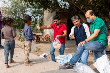 NOIDA, UTTAR PRADESH, INDIA - Kasım 2020: Hindistan 'daki sivil toplum örgütü gençlerinden oluşan bir grup, salgın sırasında yoksul çocuklara ve gecekondu halkına yiyecek dağıtıyor. Zor zamanlarda topluma geri vermek.