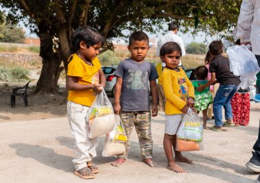 NOIDA, UTTAR PRADESH, INDIA - NOVEMBER 2020: Hindistan 'da Corona salgını sırasında gönüllülerin dağıttığı yiyecekleri toplamak için kenar mahalle veya köy bölgesinden gelen genç çocuklar veya öğrenciler. Topluma geri vermek..
