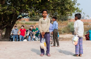 NOIDA, UTTAR PRADESH, INDIA - NOVEMBER 2020: Hindistan 'ın köy veya gecekondu mahallelerinden gelen genç çocukların portresi, kış boyunca okulda duruyor ve salgın sırasında sivil toplum örgütü tarafından dağıtılıyor. Zor zamanlarda topluma geri vermek.