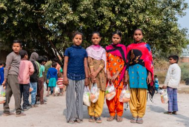 NOIDA, UTTAR PRADESH, INDIA - NOVEMBER 2020: Hindistan 'da Corona salgını sırasında gönüllülerin dağıttığı yiyecekleri toplamak için kenar mahalle veya köy bölgesinden gelen genç çocuklar veya öğrenciler. Topluma geri vermek..