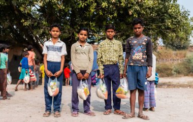 NOIDA, UTTAR PRADESH, INDIA - NOVEMBER 2020: Hindistan 'da Corona salgını sırasında gönüllülerin dağıttığı yiyecekleri toplamak için kenar mahalle veya köy bölgesinden gelen genç çocuklar veya öğrenciler. Topluma geri vermek..