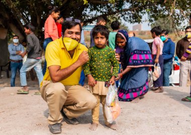 NOIDA, UTTAR PRADESH, INDIA - NOVEMBER 2020: Fakir çocukları kaliteli eğitimle eğitmek için salgın sırasında okulda öğrenci veya genç bir kızla Hintli öğretmen. Zor zamanlarda topluma geri vermek.