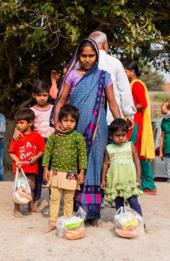 NOIDA, UTTAR PRADESH, INDIA - Kasım 2020: Çocuğuyla birlikte Sari 'deki açık alanda duran köy bölgesinden Hintli bir kadının portresi. Eğitim için okulda çocuklarına bakıyor..