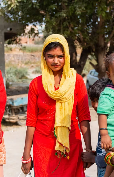 NOIDA, UTTAR PRADESH, Hindistan - Kasım 2020: Evlerinin önünde dikilen renkli elbiseli yerli kadınların portresi.