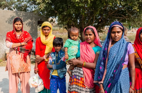 NOIDA, UTTAR PRADESH, Hindistan - Kasım 2020: Evlerinin önünde dikilen renkli elbiseli yerli kadınların portresi.