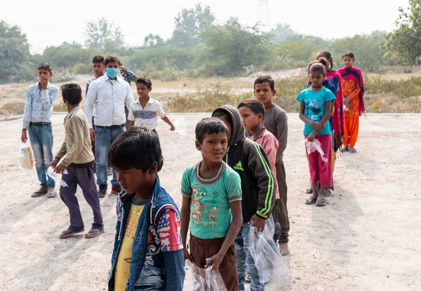 NOIDA, UTTAR PRADESH, INDIA - NOVEMBER 2020: Hindistan 'da Corona salgını sırasında gönüllülerin dağıttığı yiyecekleri toplamak için kenar mahalle veya köy bölgesinden gelen genç çocuklar veya öğrenciler. Topluma geri vermek..