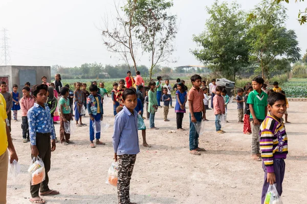 NOIDA, UTTAR PRADESH, INDIA - NOVEMBER 2020: Hindistan 'da Corona salgını sırasında gönüllülerin dağıttığı yiyecekleri toplamak için kenar mahalle veya köy bölgesinden gelen genç çocuklar veya öğrenciler. Topluma geri vermek..