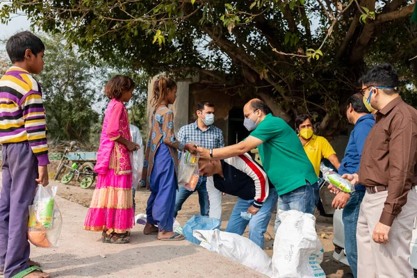 NOIDA, UTTAR PRADESH, INDIA - Kasım 2020: Hindistan 'daki sivil toplum örgütü gençlerinden oluşan bir grup, salgın sırasında yoksul çocuklara ve gecekondu halkına yiyecek dağıtıyor. Zor zamanlarda topluma geri vermek.