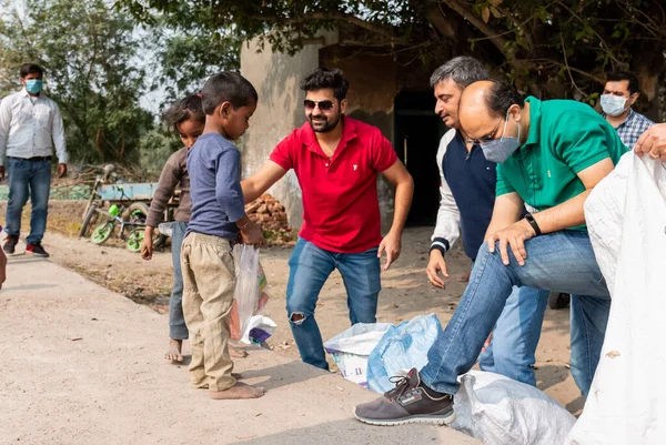 NOIDA, UTTAR PRADESH, INDIA - Kasım 2020: Hindistan 'daki sivil toplum örgütü gençlerinden oluşan bir grup, salgın sırasında yoksul çocuklara ve gecekondu halkına yiyecek dağıtıyor. Zor zamanlarda topluma geri vermek.