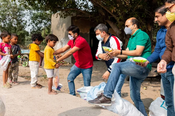 NOIDA, UTTAR PRADESH, INDIA - Kasım 2020: Hindistan 'daki sivil toplum örgütü gençlerinden oluşan bir grup, salgın sırasında yoksul çocuklara ve gecekondu halkına yiyecek dağıtıyor. Zor zamanlarda topluma geri vermek.