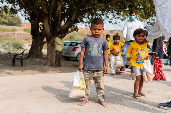 NOIDA, UTTAR PRADESH, INDIA - NOVEMBER 2020: Hindistan 'da Corona salgını sırasında gönüllülerin dağıttığı yiyecekleri toplamak için kenar mahalle veya köy bölgesinden gelen genç çocuklar veya öğrenciler. Topluma geri vermek..