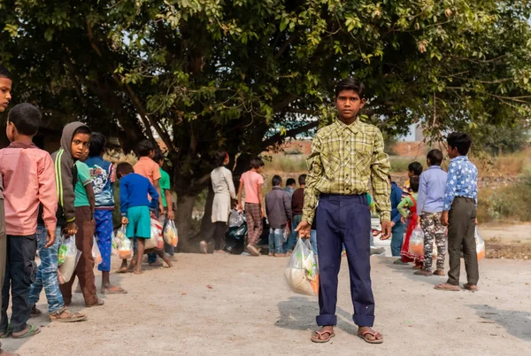 NOIDA, UTTAR PRADESH, INDIA - NOVEMBER 2020: Hindistan 'da Corona salgını sırasında gönüllülerin dağıttığı yiyecekleri toplamak için kenar mahalle veya köy bölgesinden gelen genç çocuklar veya öğrenciler. Topluma geri vermek..