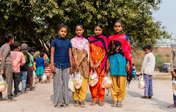 NOIDA, UTTAR PRADESH, INDIA - NOVEMBER 2020: Hindistan 'da Corona salgını sırasında gönüllülerin dağıttığı yiyecekleri toplamak için kenar mahalle veya köy bölgesinden gelen genç çocuklar veya öğrenciler. Topluma geri vermek..