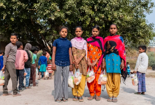 NOIDA, UTTAR PRADESH, INDIA - NOVEMBER 2020: Hindistan 'da Corona salgını sırasında gönüllülerin dağıttığı yiyecekleri toplamak için kenar mahalle veya köy bölgesinden gelen genç çocuklar veya öğrenciler. Topluma geri vermek..