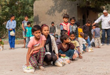 NOIDA, UTTAR PRADESH, INDIA - NOVEMBER 2020: Hindistan 'da Corona salgını sırasında gönüllülerin dağıttığı yiyecekleri toplamak için kenar mahalle veya köy bölgesinden gelen genç çocuklar veya öğrenciler. Topluma geri vermek..