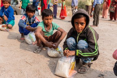 NOIDA, UTTAR PRADESH, INDIA - NOVEMBER 2020: Hindistan 'da Corona salgını sırasında gönüllülerin dağıttığı yiyecekleri toplamak için kenar mahalle veya köy bölgesinden gelen genç çocuklar veya öğrenciler. Topluma geri vermek..