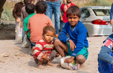 NOIDA, UTTAR PRADESH, INDIA - NOVEMBER 2020: Hindistan 'da Corona salgını sırasında gönüllülerin dağıttığı yiyecekleri toplamak için kenar mahalle veya köy bölgesinden gelen genç çocuklar veya öğrenciler. Topluma geri vermek..