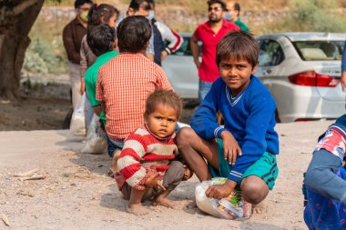 NOIDA, UTTAR PRADESH, INDIA - NOVEMBER 2020: Hindistan 'da Corona salgını sırasında gönüllülerin dağıttığı yiyecekleri toplamak için kenar mahalle veya köy bölgesinden gelen genç çocuklar veya öğrenciler. Topluma geri vermek..