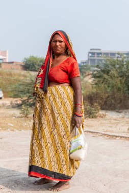 NOIDA, UTTAR PRADESH, Hindistan - Kasım 2020: Evlerinin önünde dikilen renkli elbiseli yerli kadınların portresi.