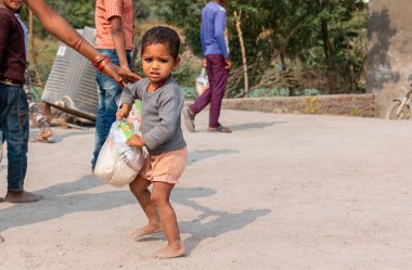 NOIDA, UTTAR PRADESH, INDIA - NOVEMBER 2020: Hindistan 'da Corona salgını sırasında gönüllülerin dağıttığı yiyecekleri toplamak için kenar mahalle veya köy bölgesinden gelen genç çocuklar veya öğrenciler. Topluma geri vermek..