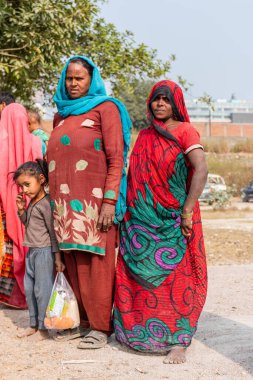 NOIDA, UTTAR PRADESH, Hindistan - Kasım 2020: Evlerinin önünde dikilen renkli elbiseli yerli kadınların portresi.