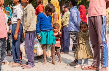 NOIDA, UTTAR PRADESH, INDIA - NOVEMBER 2020: Hindistan 'da Corona salgını sırasında gönüllülerin dağıttığı yiyecekleri toplamak için kenar mahalle veya köy bölgesinden gelen genç çocuklar veya öğrenciler. Topluma geri vermek..