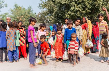 NOIDA, UTTAR PRADESH, INDIA - NOVEMBER 2020: Hindistan 'da Corona salgını sırasında gönüllülerin dağıttığı yiyecekleri toplamak için kenar mahalle veya köy bölgesinden gelen genç çocuklar veya öğrenciler. Topluma geri vermek..