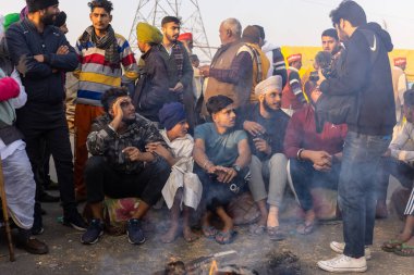 NEW DELHI, INDIA - HAZİRAN 2021: Hint Sih çiftçisi yeni çiftlik yasasına karşı protesto sırasında kamp ateşinin yanında oturuyor. Hindistan 'ın dört bir yanından çiftçiler yeni tarım yasasını protesto ediyorlar..