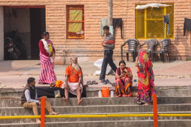 HARIDWAR, UTTARAKHAND, INDIA - Şubat 2021: Kimliği belirsiz bir grup erkek ve kadın Haridwar şehrinde kumbh mela sırasında Ganga nehrinin kenarında oturuyorlar.