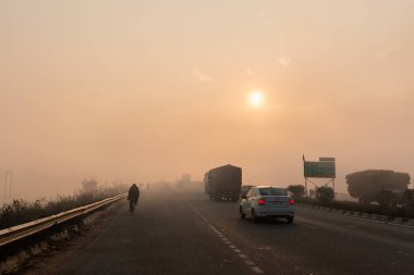 UTTAR PRADESH, Hindistan - 2020 ARALIK: Hint Karayolları, sisli ve kış sabahı gün doğumunda Hindistan yollarının güzel manzarası. Otobanlarda çalışan araçlar.