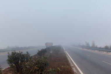 UTTAR PRADESH, Hindistan - 2020 ARALIK: Hint Karayolları, sisli ve kış sabahı gün doğumunda Hindistan yollarının güzel manzarası. Otobanlarda çalışan araçlar.
