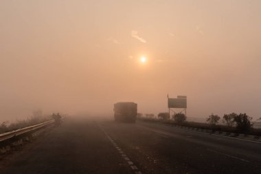 UTTAR PRADESH, Hindistan - 2020 ARALIK: Hint Karayolları, sisli ve kış sabahı gün doğumunda Hindistan yollarının güzel manzarası. Otobanlarda çalışan araçlar.