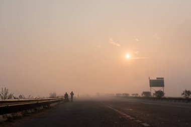 UTTAR PRADESH, Hindistan - 2020 ARALIK: Hint Karayolları, sisli ve kış sabahı gün doğumunda Hindistan yollarının güzel manzarası. Otobanlarda çalışan araçlar.