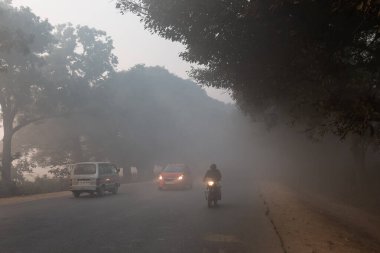 UTTAR PRADESH, Hindistan - 2020 ARALIK: Hint Karayolları, sisli ve kış sabahı gün doğumunda Hindistan yollarının güzel manzarası. Otobanlarda çalışan araçlar.