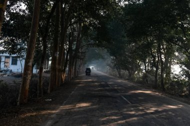 UTTAR PRADESH, Hindistan - 2020 ARALIK: Hint Karayolları, sisli ve kış sabahı gün doğumunda Hindistan yollarının güzel manzarası. Otobanlarda çalışan araçlar.